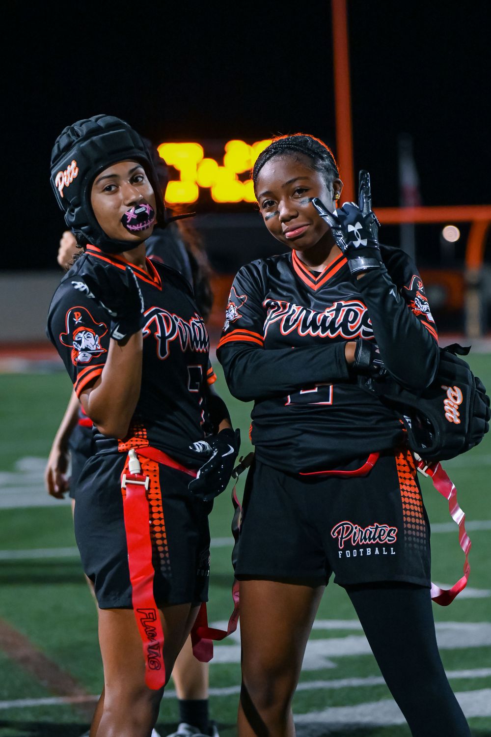 Football team members celebrate and embrace on the sidelines during a night game.
