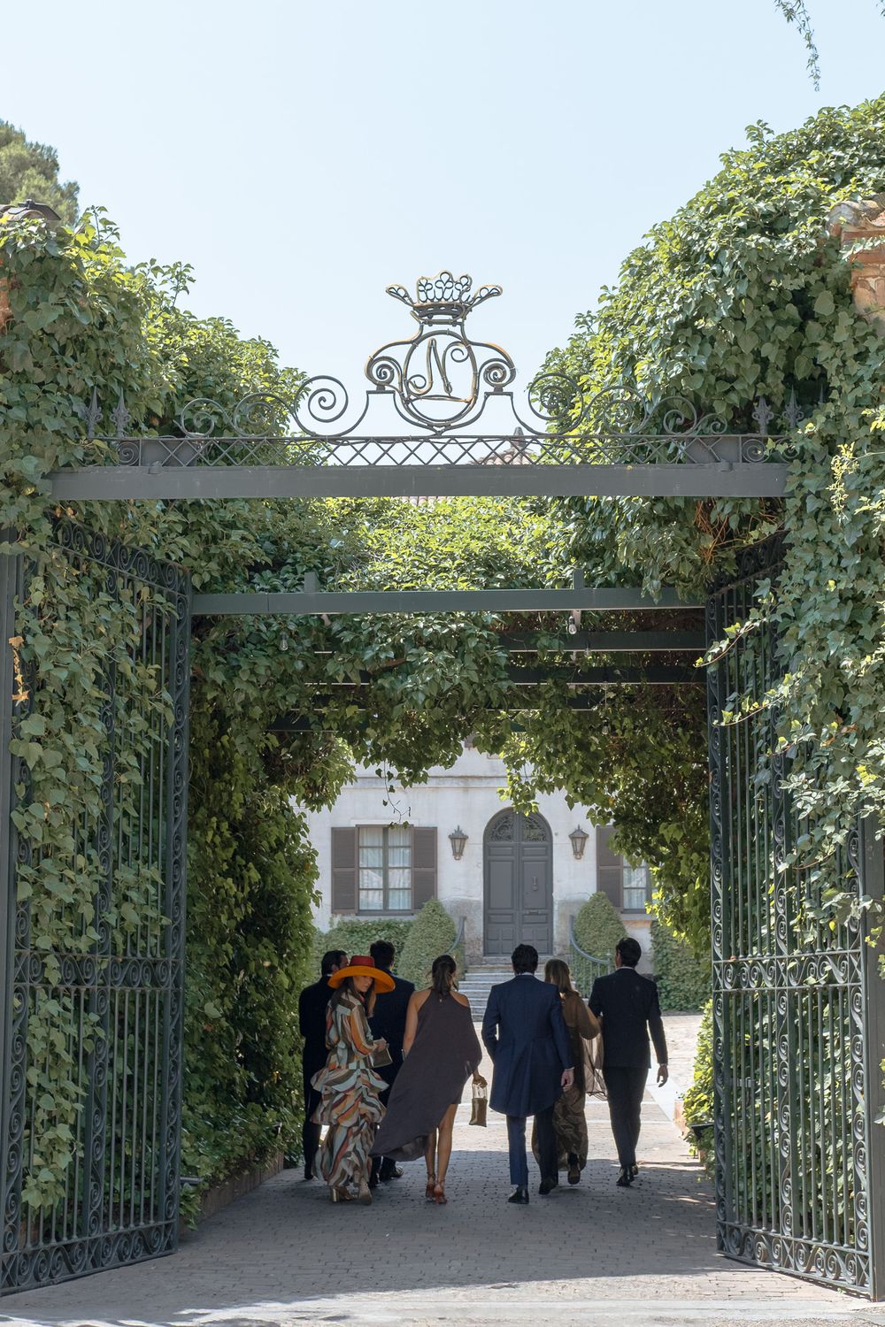 Ornate garden archway with climbing vines leading to a white building.