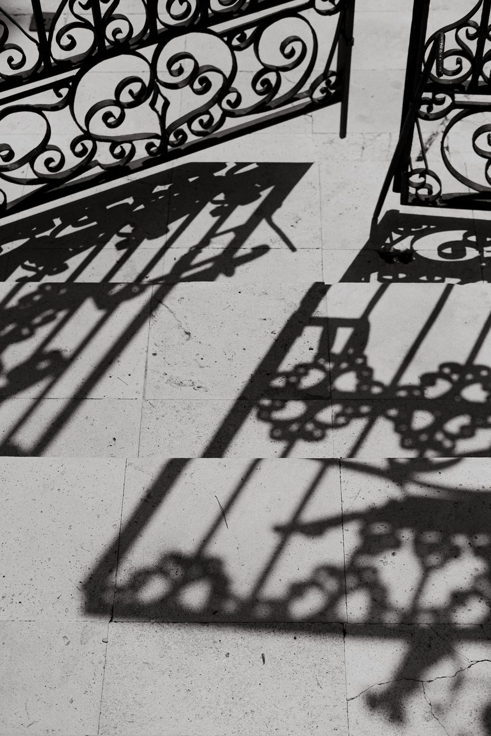 Decorative wrought iron railing casting intricate shadow patterns on a light surface.
