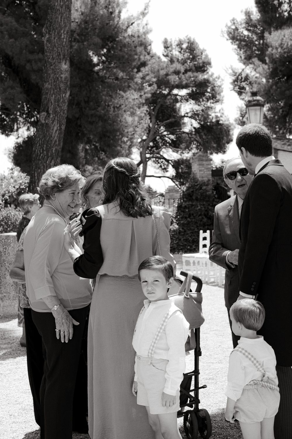 Candid black and white photo of wedding guests gathered outdoors.
