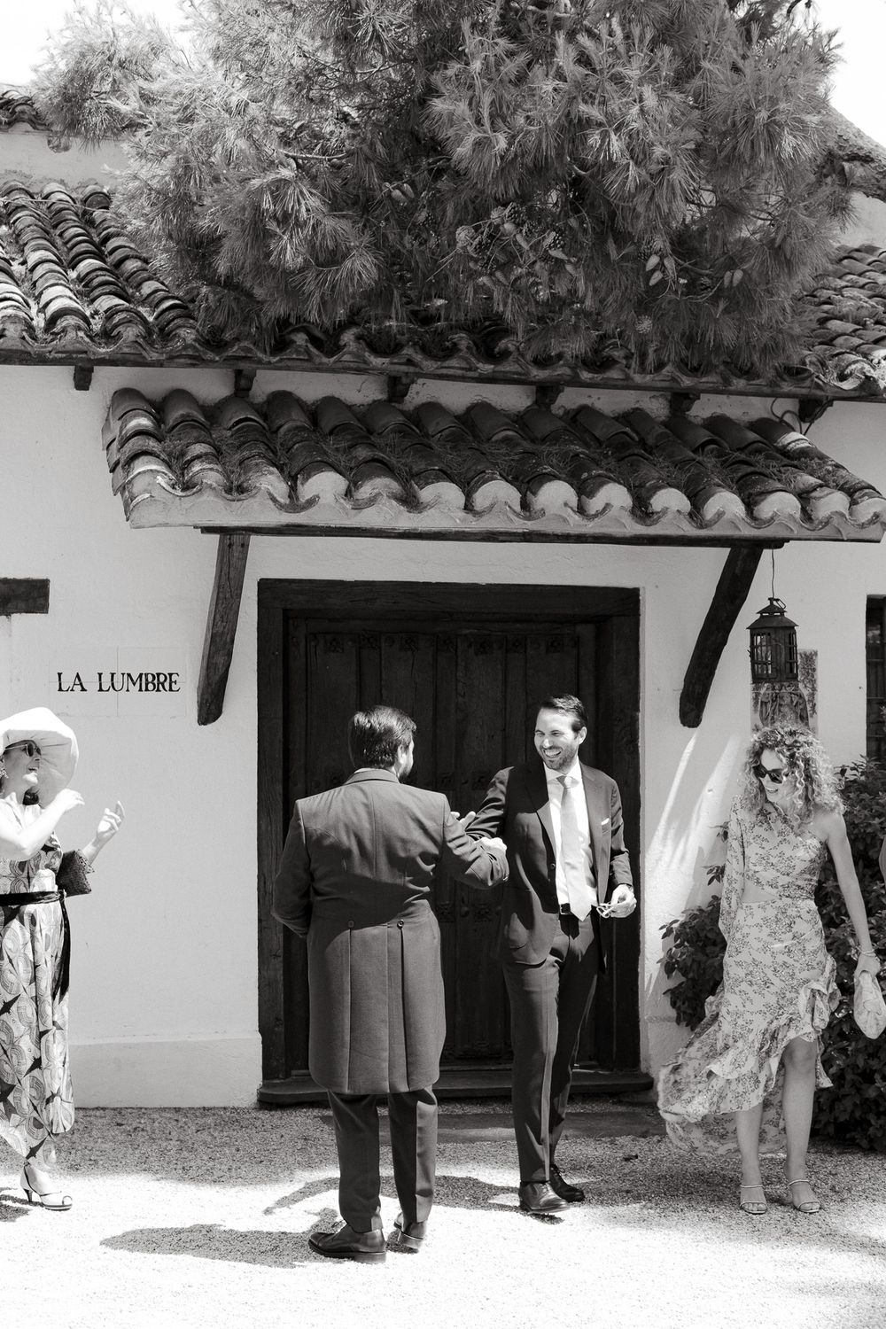 People gathered outside a Spanish-style building entrance marked 'La Lumbre'.