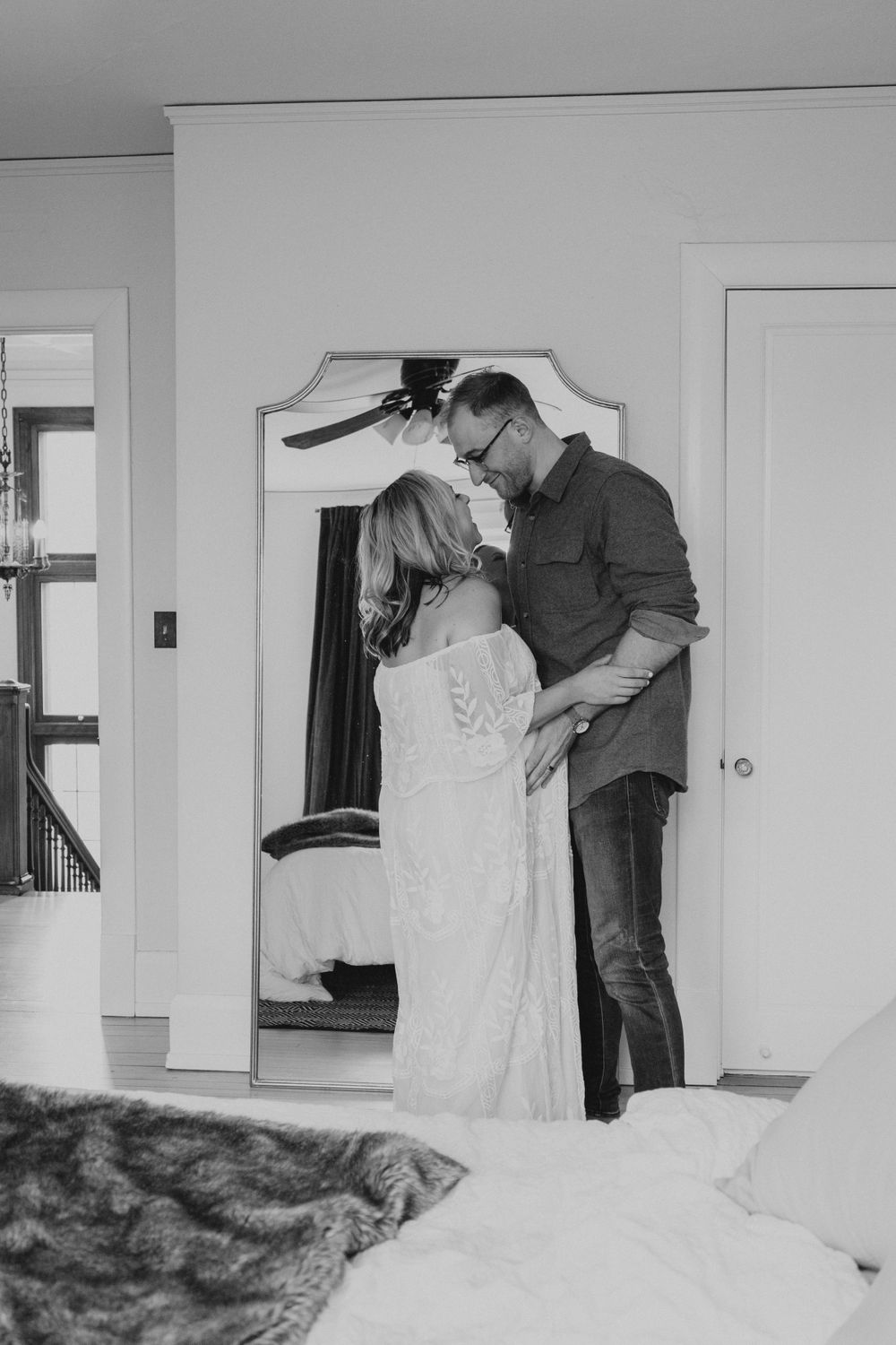 A romantic black and white portrait of a couple sharing an intimate moment in a doorway.