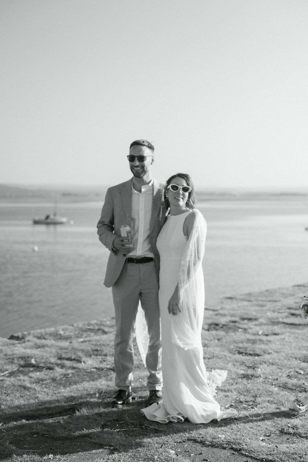 Couple in wedding attire posing on a scenic pier after their Findhorn Wedding.