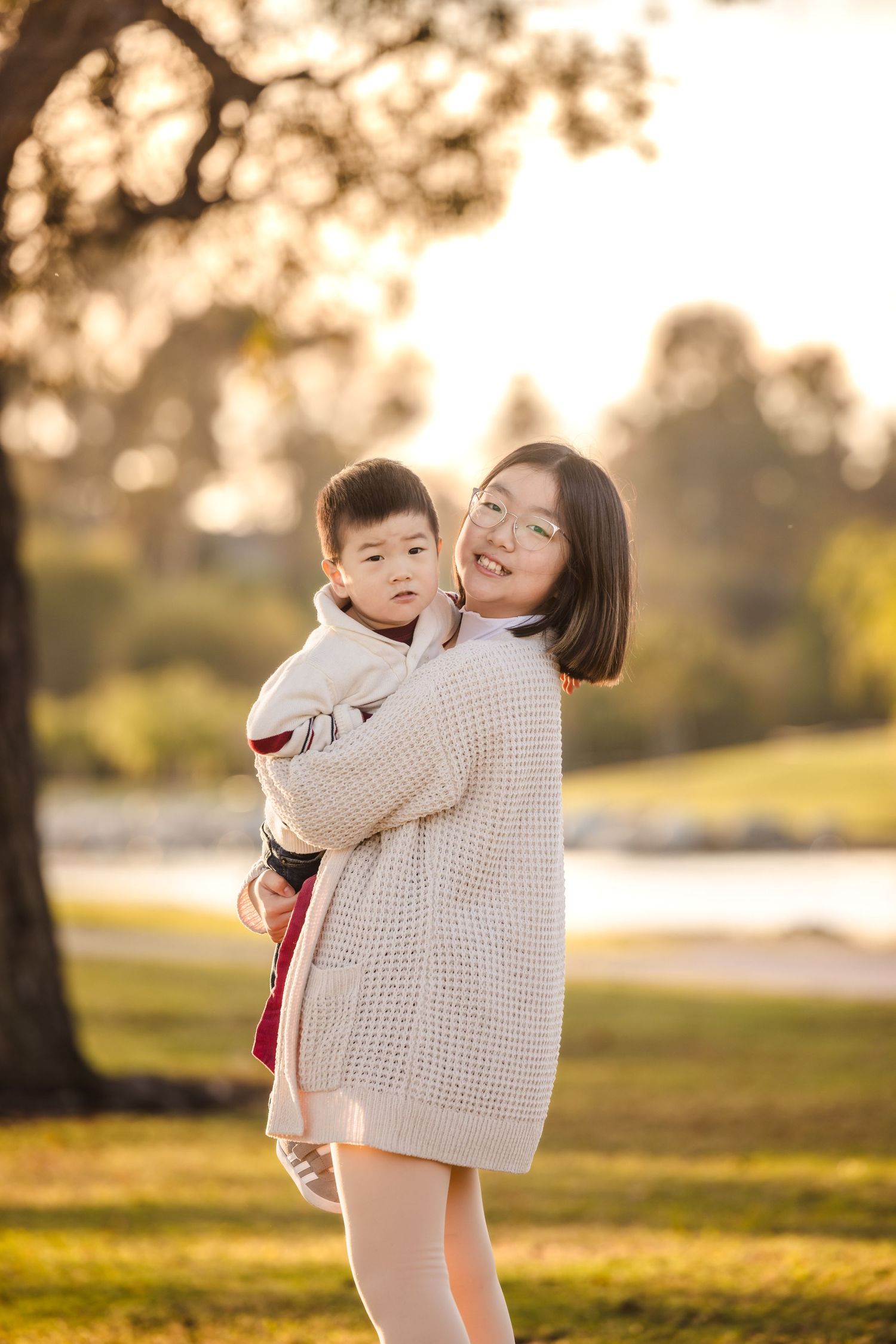 Parent and child share a loving embrace in a sunlit park during golden hour.