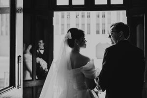 Black and white image of a wedding couple silhouetted against bright windows.