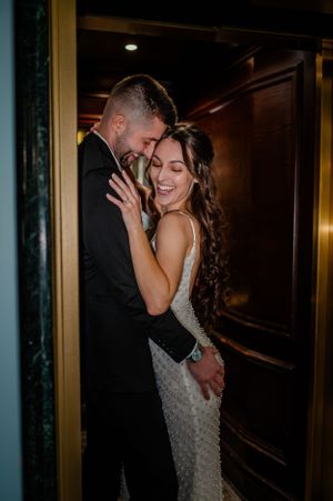 Intimate moment between couple in formal wear near dimly lit hallway.