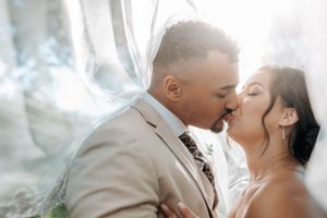 A couple shares a romantic kiss on their wedding day with dreamy smoke effects in the background.