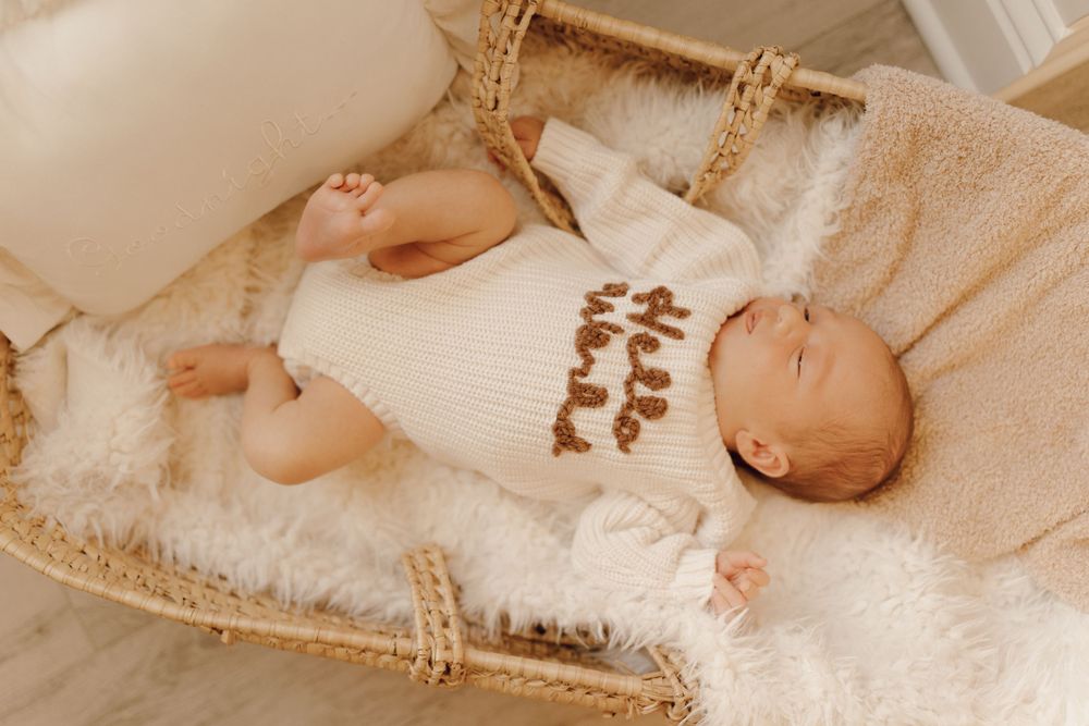Newborn baby sleeping peacefully on a soft blanket, captured in a cozy indoor photoshoot.