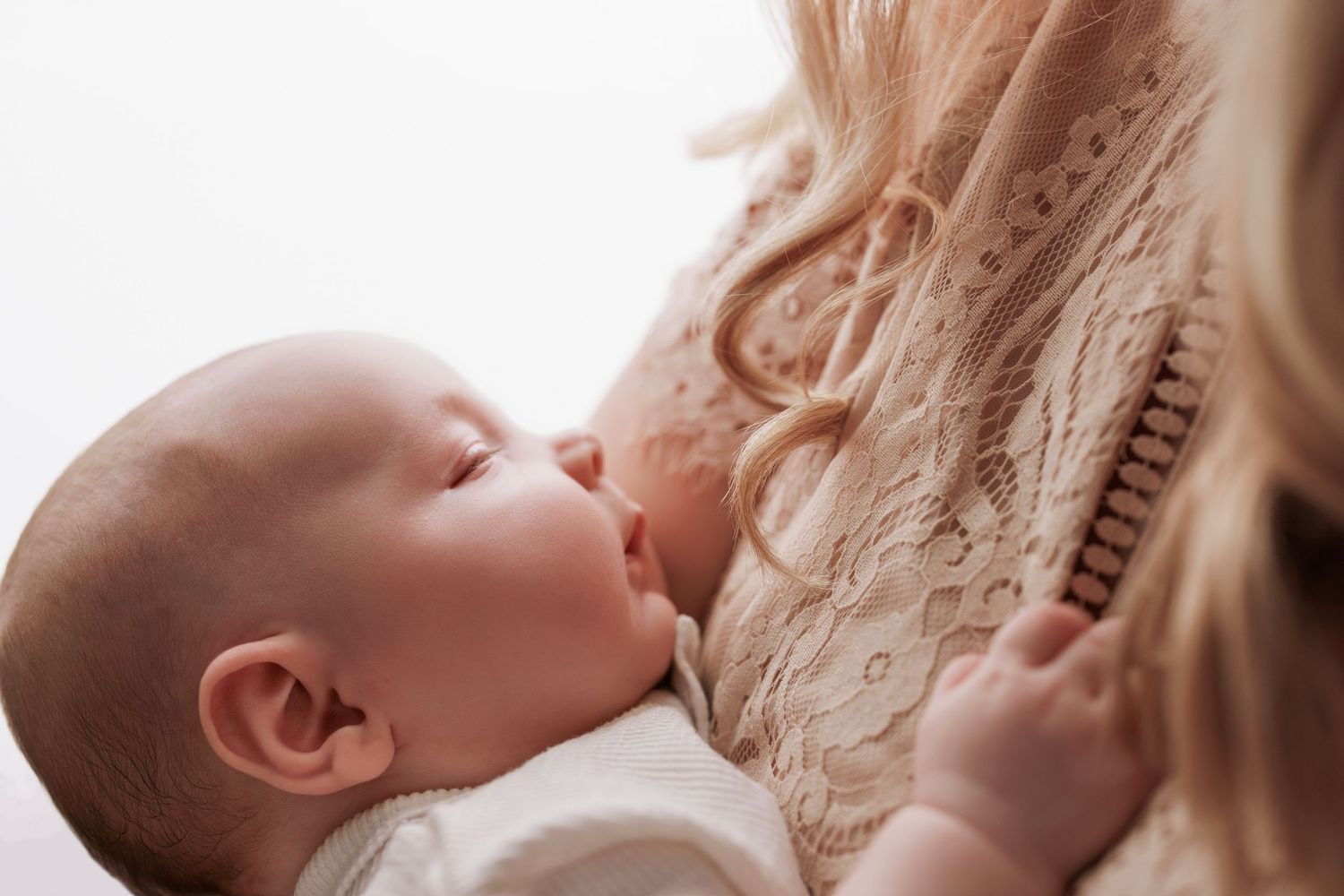 A close-up shot of a baby breastfeeding while nursing in soft natural light.