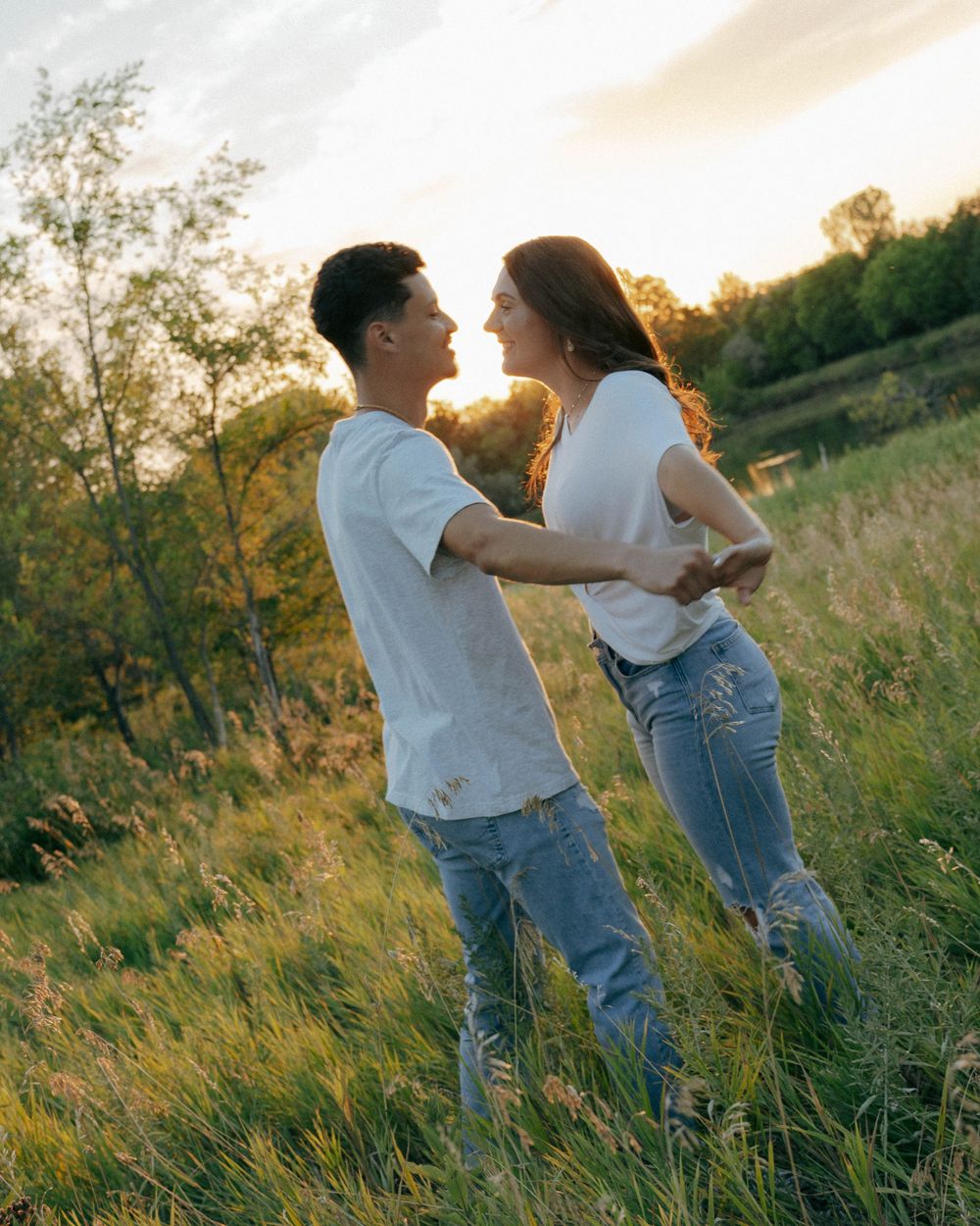 Playful moment captured in golden sunlight on a grassy hillside during sunset.