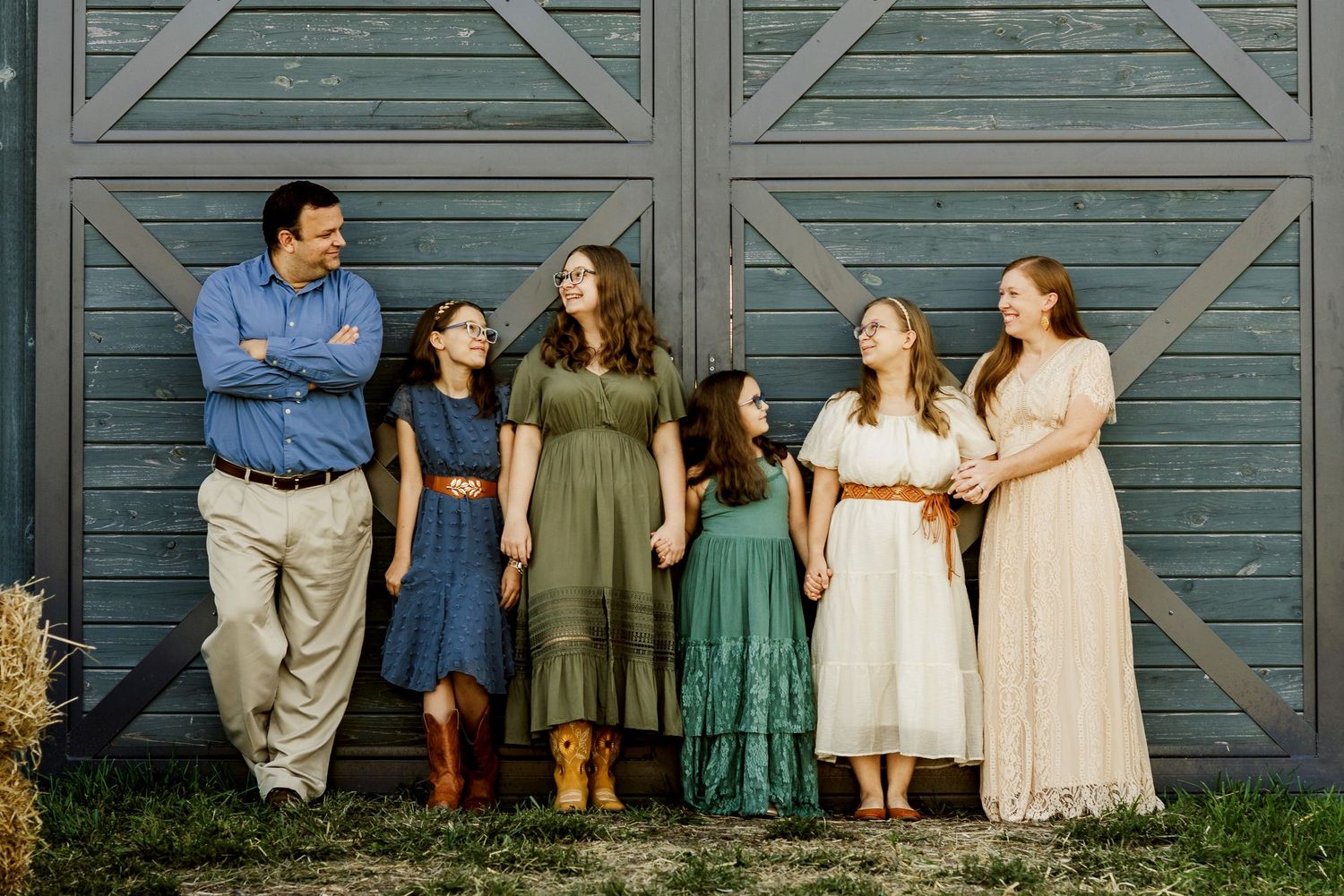 A family portrait against a weathered blue barn wall in casual farm attire.