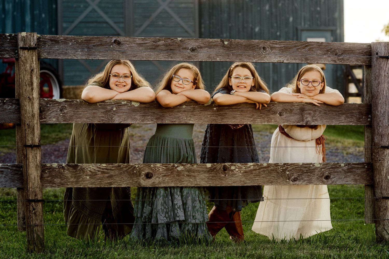People posing playfully behind a rustic wooden fence on a farm.