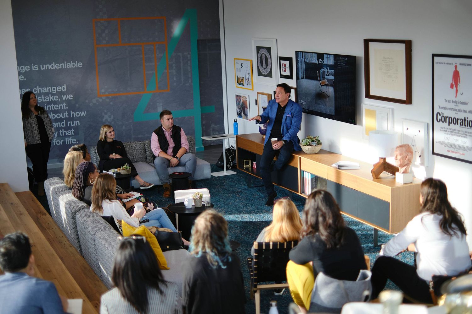 Professional gathering in modern office with projector screen and casual seating arrangement.