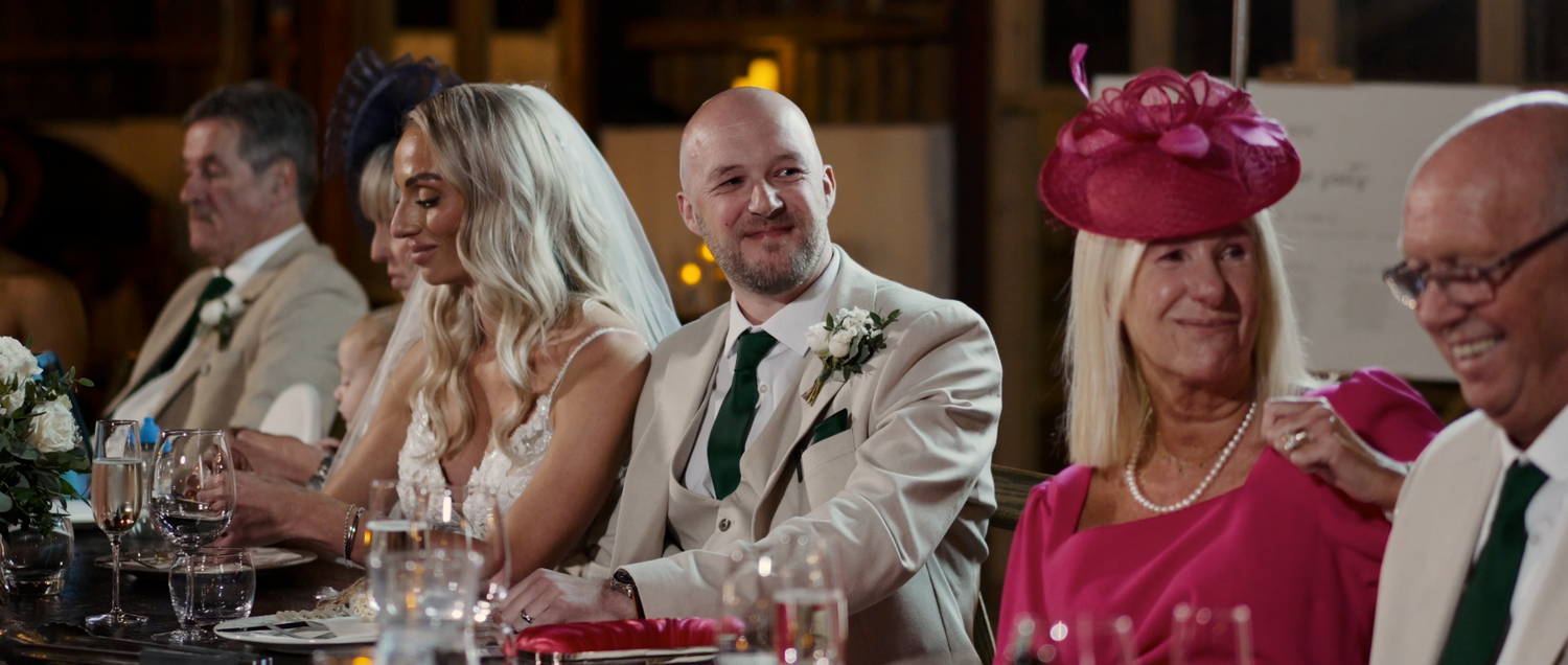 Wedding reception guests enjoying dinner and conversation at elegantly decorated tables.