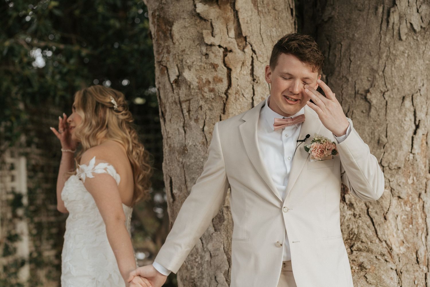 A couple shares romantic moments in a wedding photoshoot against a rustic tree backdrop at Singing Hills Golf Resort.