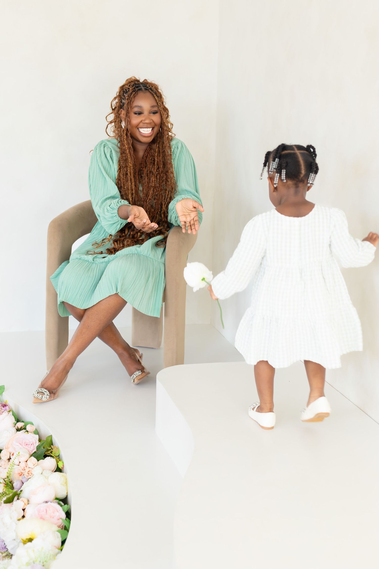 A joyful moment captured between parent and child wearing mint green and white dresses while sitting on white chairs.