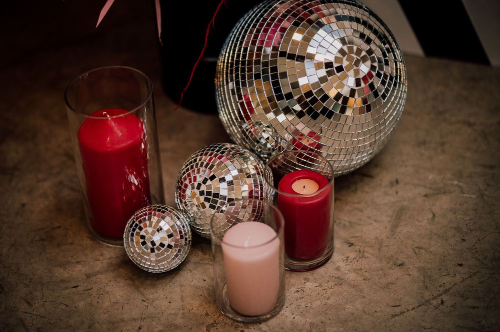 Glowing candles and silver disco balls create a festive party atmosphere on a rustic wooden surface.