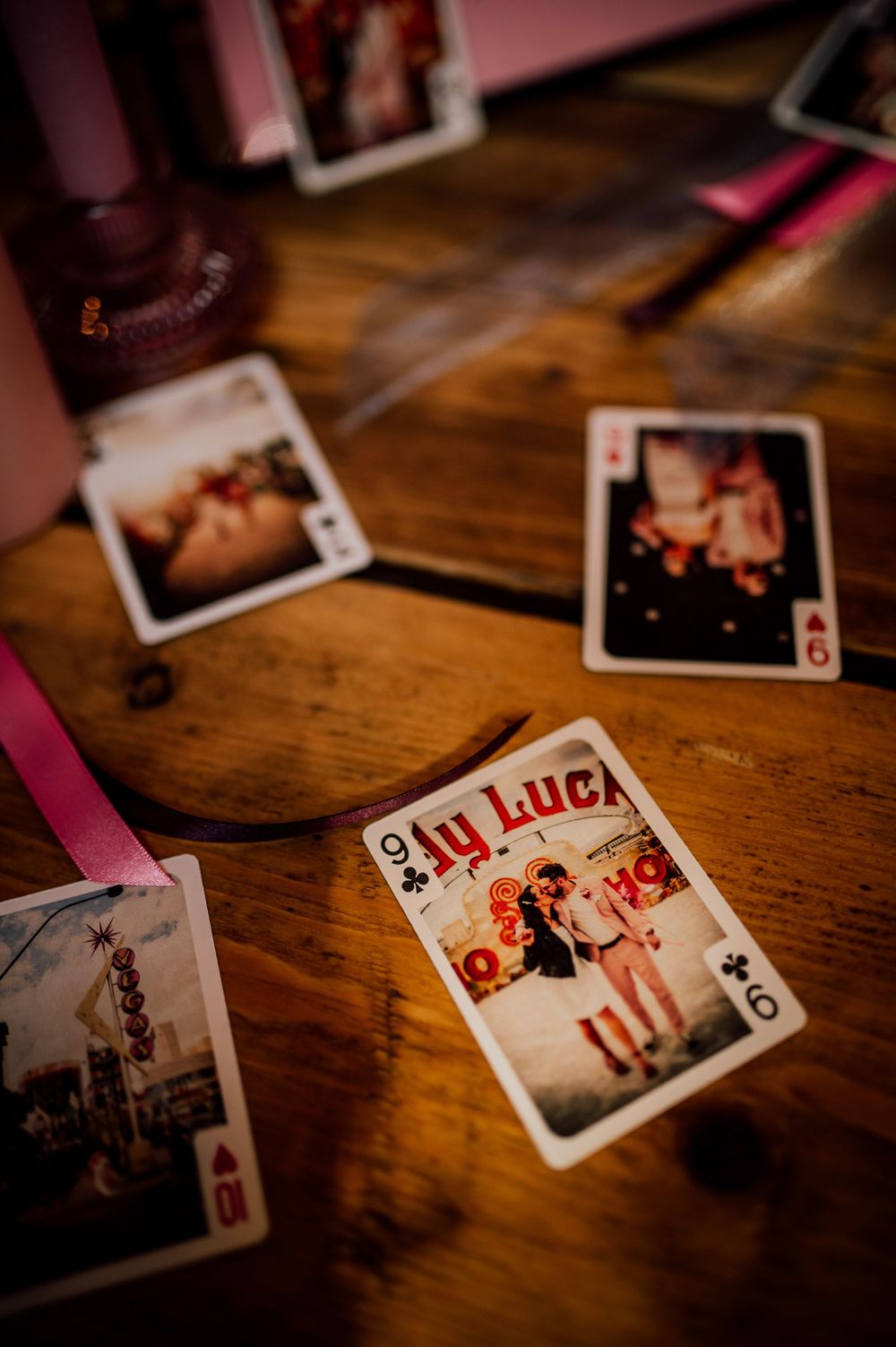Playing cards scattered on a rustic wooden table surface in warm lighting with selective focus.