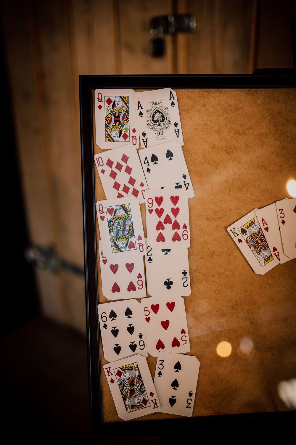Playing cards arranged in a sequence against a dark wooden surface with dramatic lighting and bokeh effects in background.