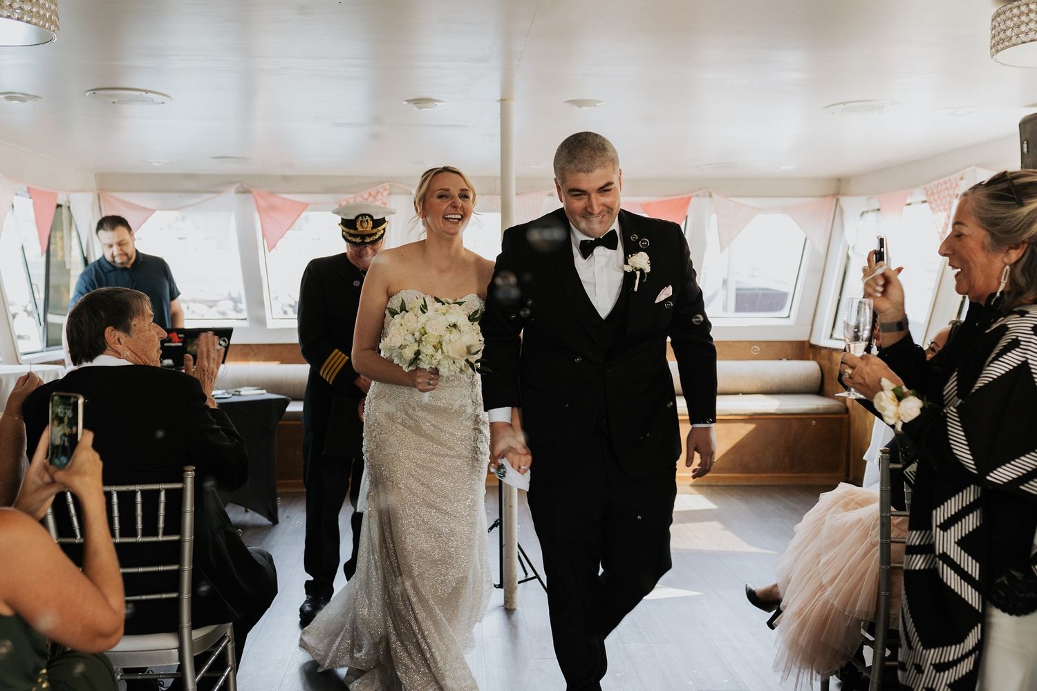 A bride and groom exit their wedding ceremony together on a boat in San Diego for Hornblower Cruises.