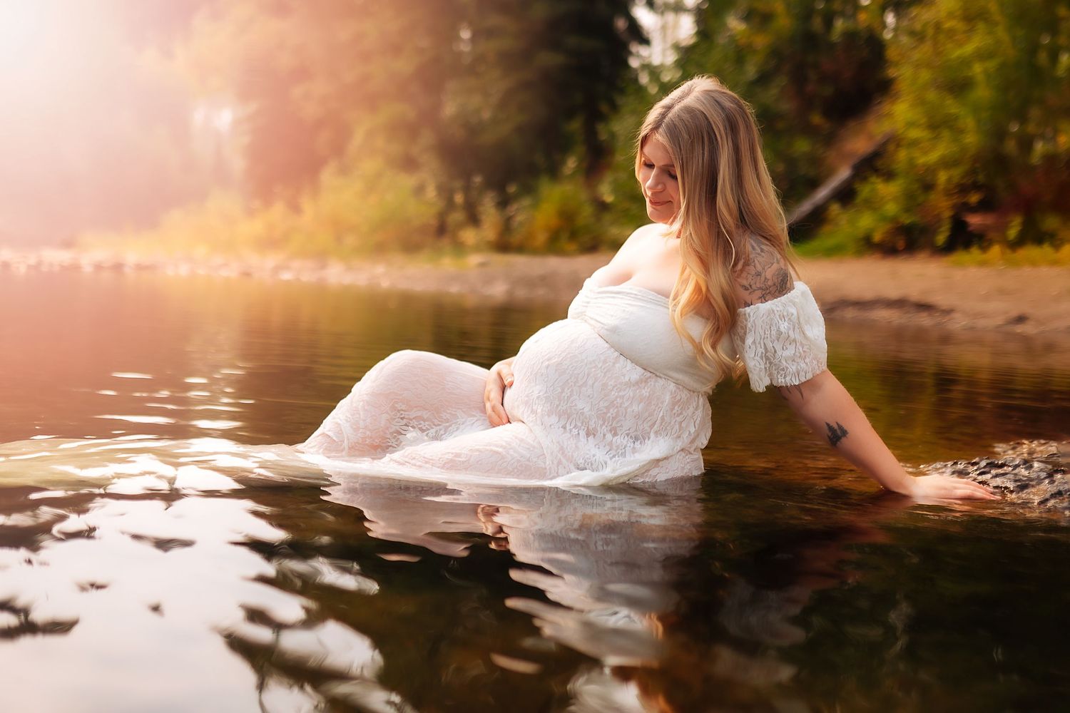 A bride in a flowing white dress floats ethereally in a serene lake during golden hour.