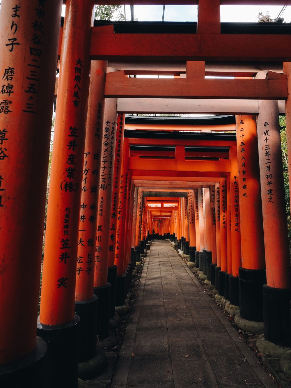 Long tunnel of vibrant orange torii gates at Fushimi Inari Shrine in Kyoto.
