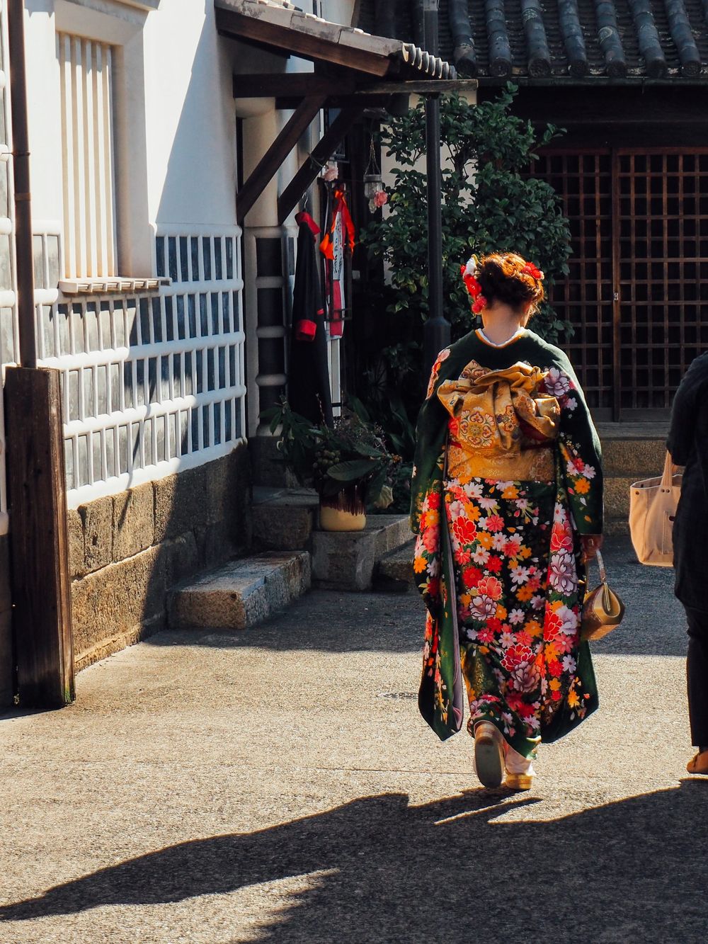 Traditional Japanese architecture with colorful kimono in sunlit courtyard.
