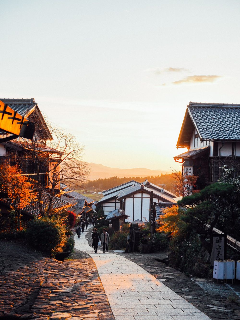 Traditional Japanese street with historic houses along a stone path during golden sunset.