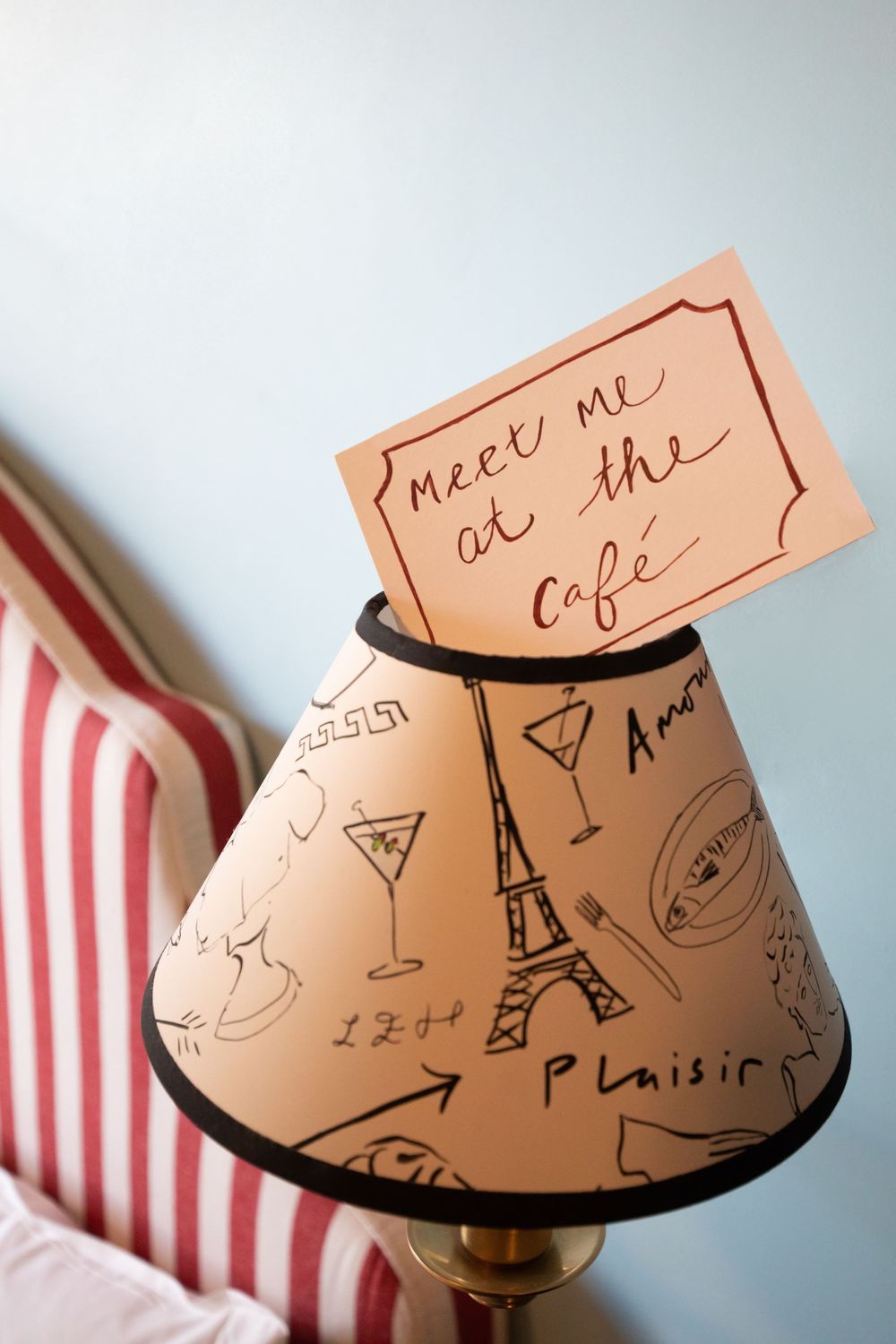 Hand-drawn doodles of the Eiffel Tower and cocktail glasses decorate a curved pink paper with casual script writing.