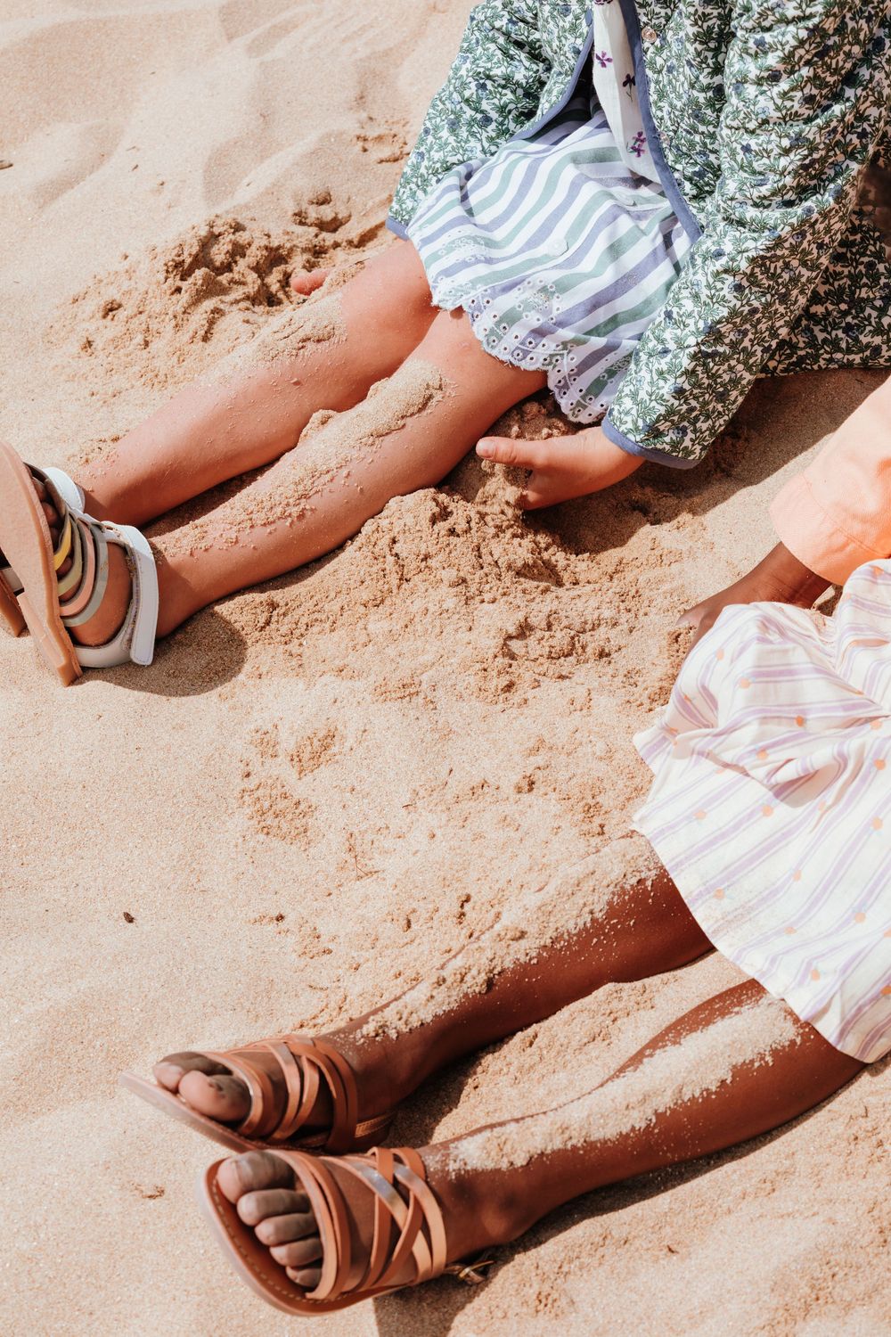 Sequence of images showing feet in brown leather sandals walking on sandy ground with a striped dress hem visible.