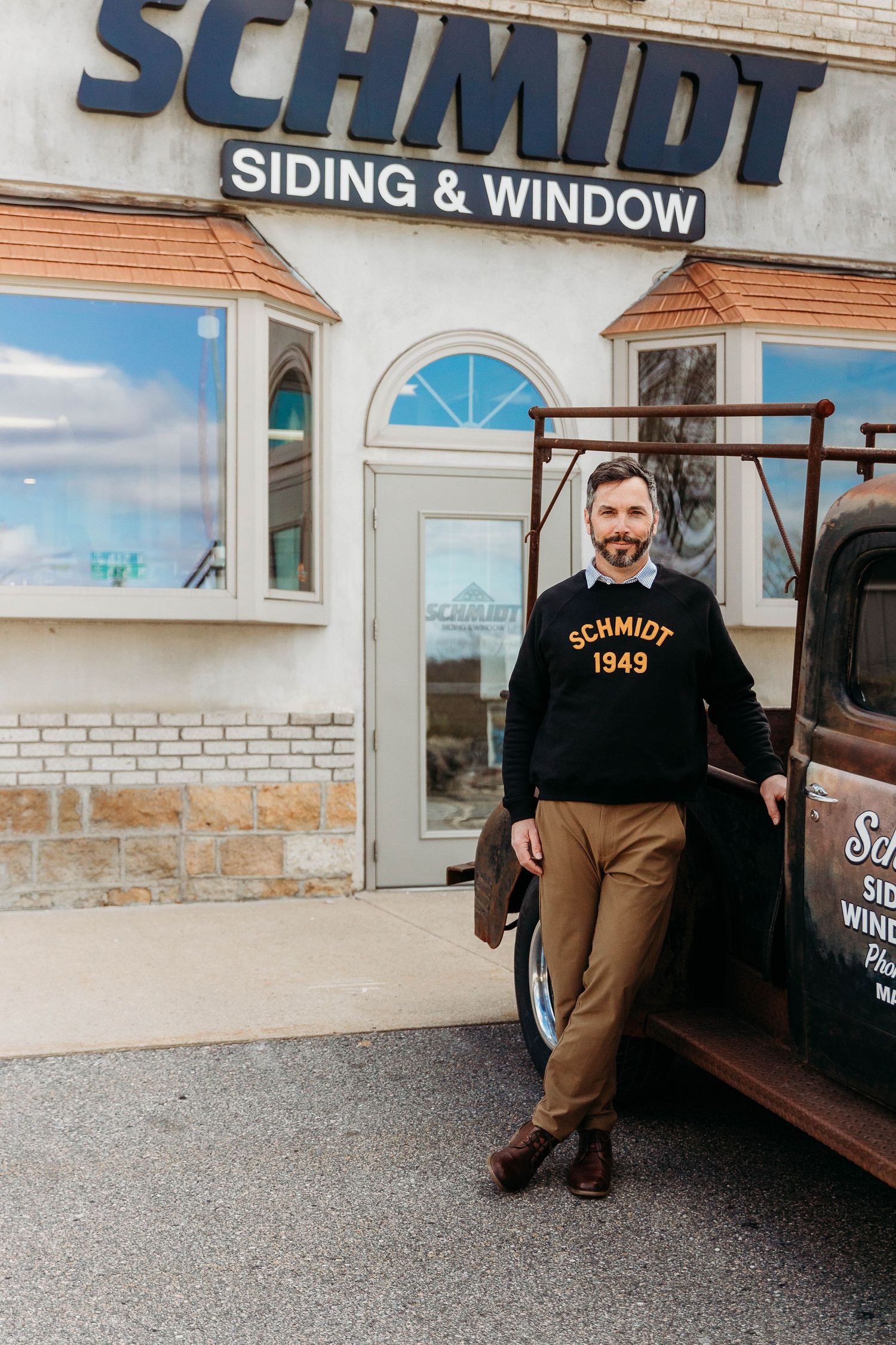 A business storefront for Schmidt Siding & Window with vintage truck parked outside the brick building entrance.