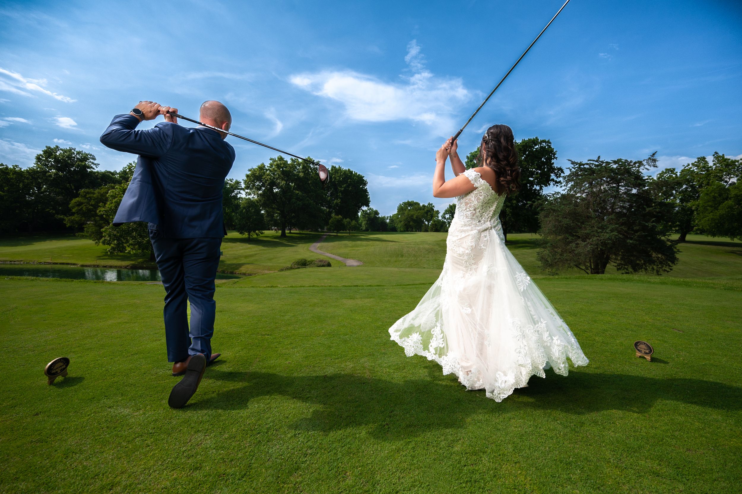 A couple in wedding attire walks across a lush green golf course on their special day.