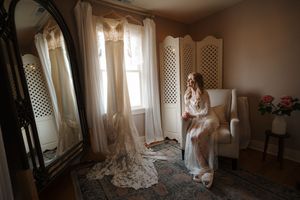 A romantic wedding scene with sunlight streaming through sheer curtains in an elegant indoor setting.