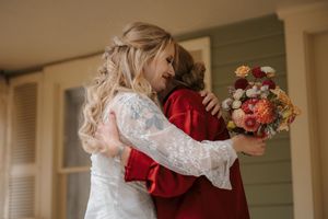 A couple embraces during a romantic dance moment in a warm-lit indoor setting with flowers visible in the background.