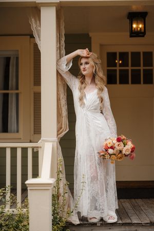 Romantic bridal portraits on a white porch with lace dress details and floral bouquet in soft natural lighting.