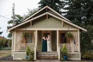 Exterior view of a charming craftsman style bungalow house with white siding and a covered front porch.