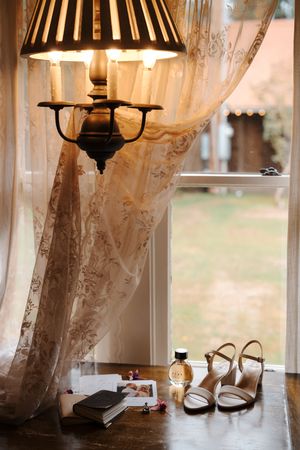 Vintage lace curtains filter sunlight through windows while table lamps cast a warm glow in an elegant room setting.