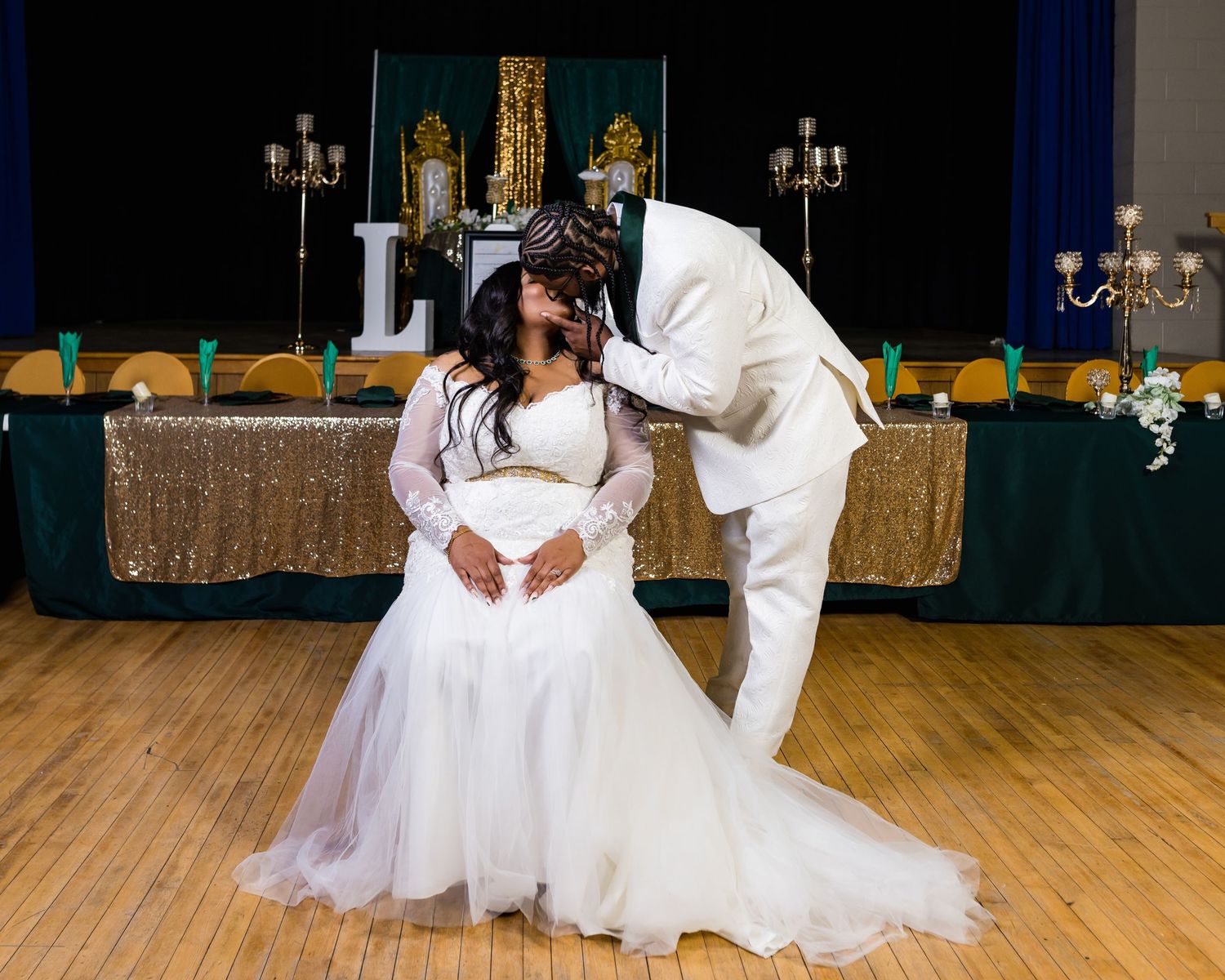 A romantic wedding moment captured on a dance floor with gold decor and candelabras in the background.