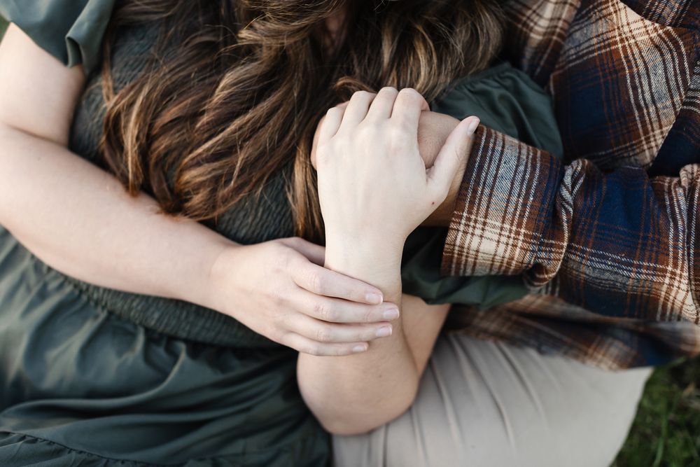 Close up shot of couple's hands embracing on a cream crochet blanket in Concord, Middlesex County for engagement photos.