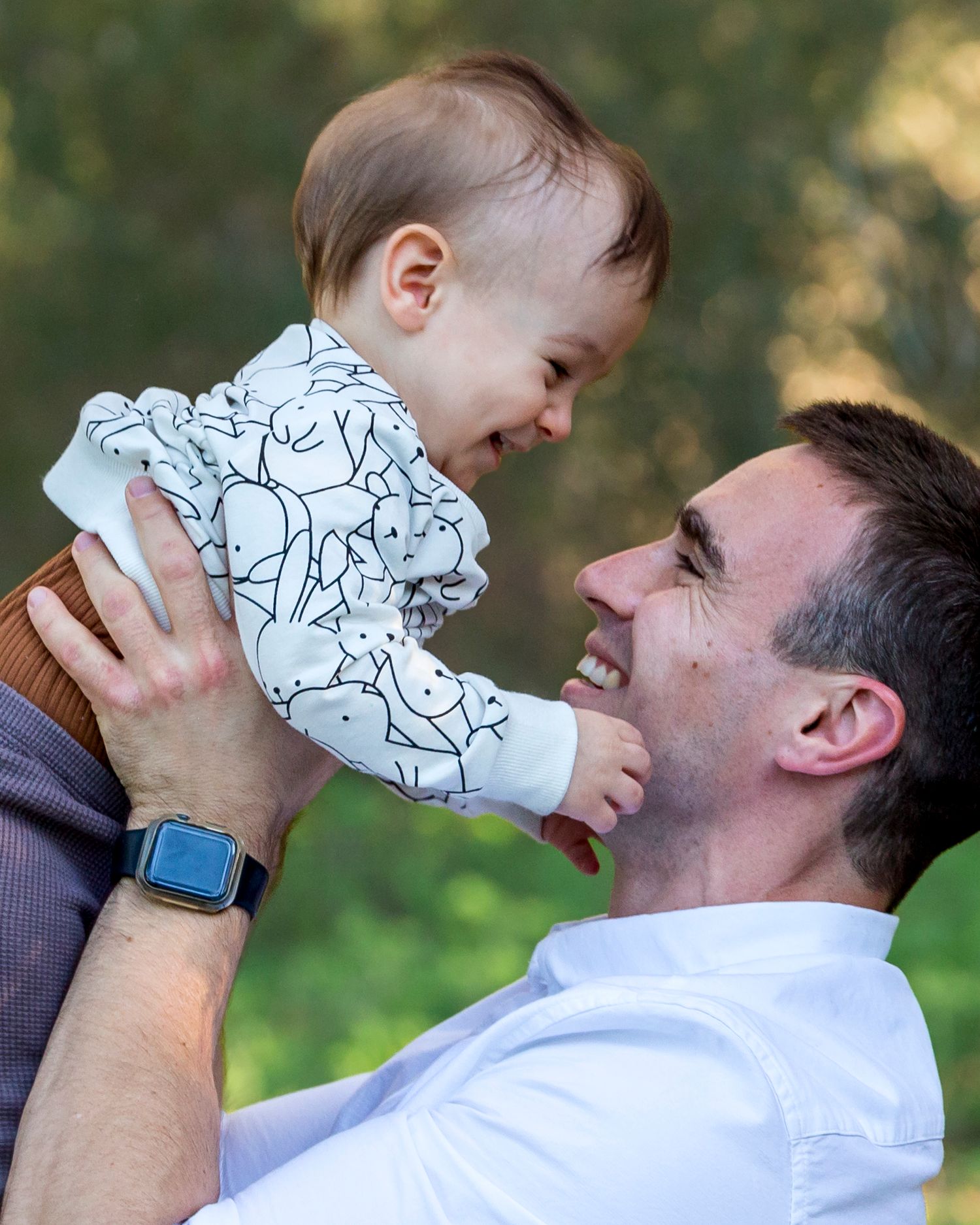 Candid moment of a father and his 12‑month‑old son smiling at each other in soft natural light