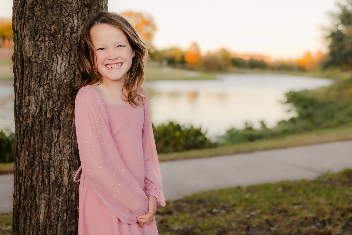 A series of outdoor autumn portraits in pink sweaters against a natural backdrop with warm sunset lighting.