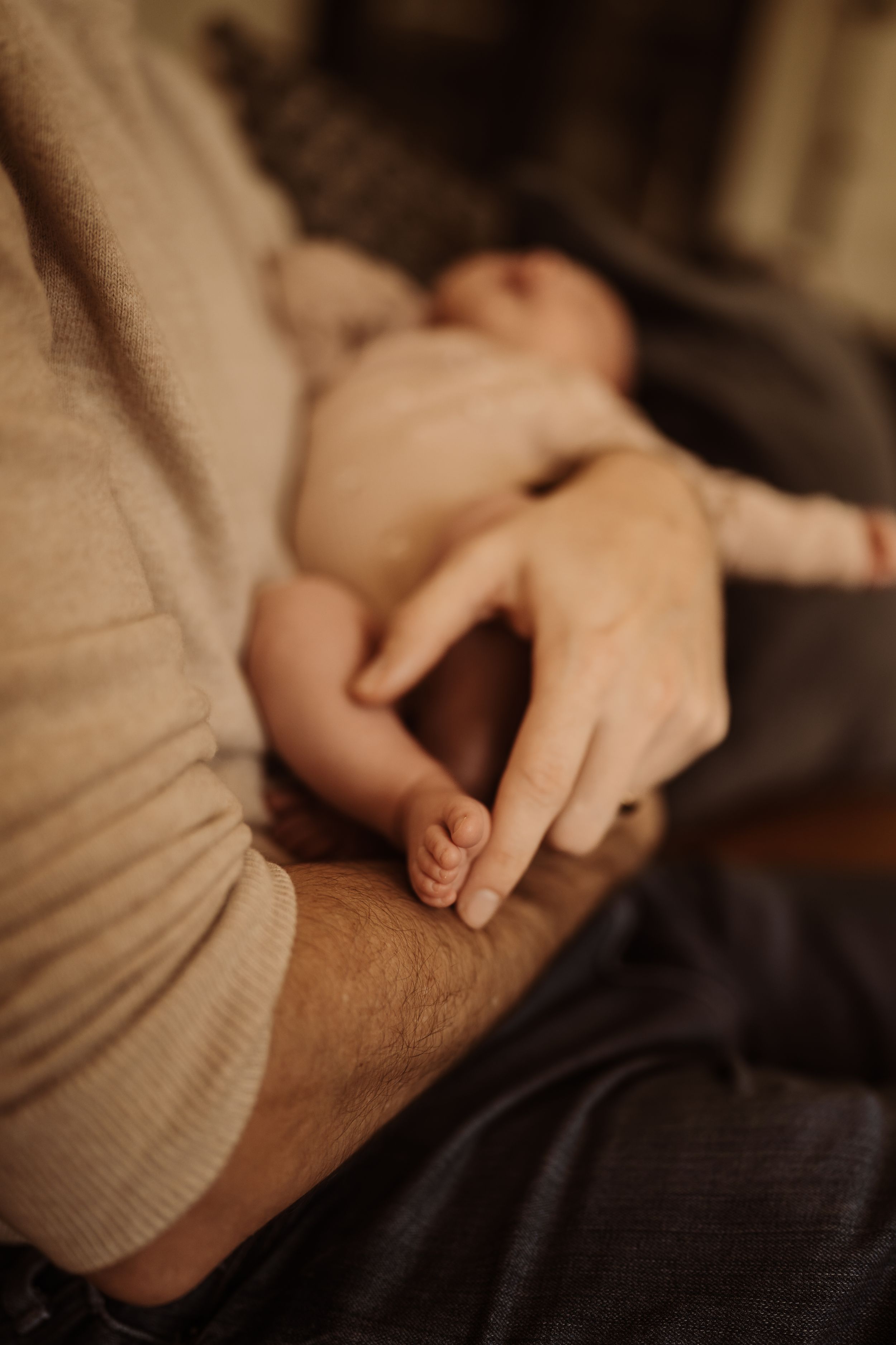 A tender moment showing a parent's hand gently holding their sleeping baby's tiny foot.