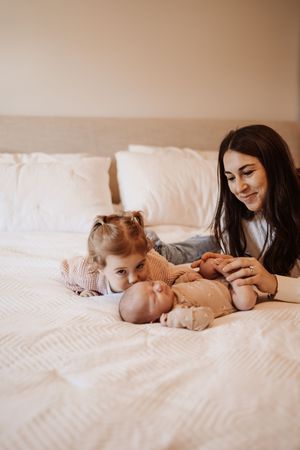A series of intimate lifestyle photos showing tender moments between parent and baby on white bedding.
