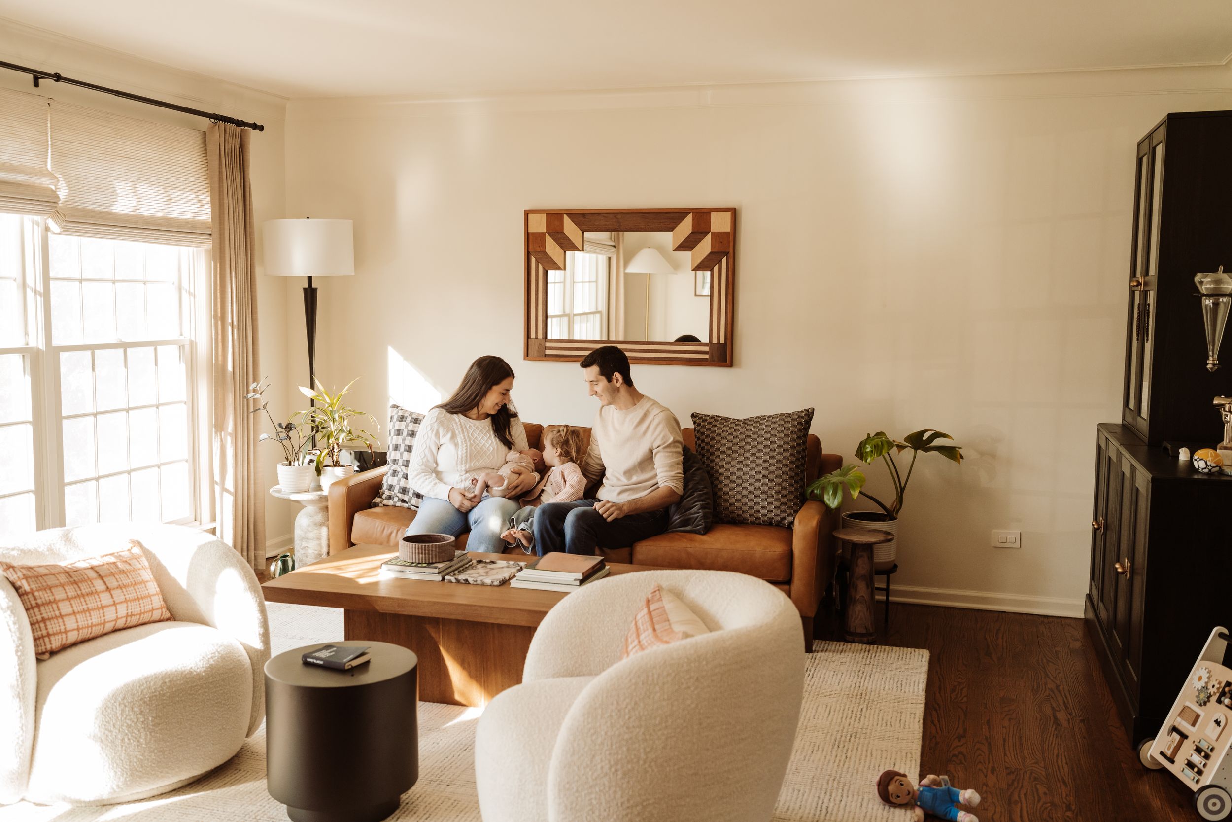 A bright and airy living room with wood trim features a comfortable sofa and natural lighting from multiple windows.