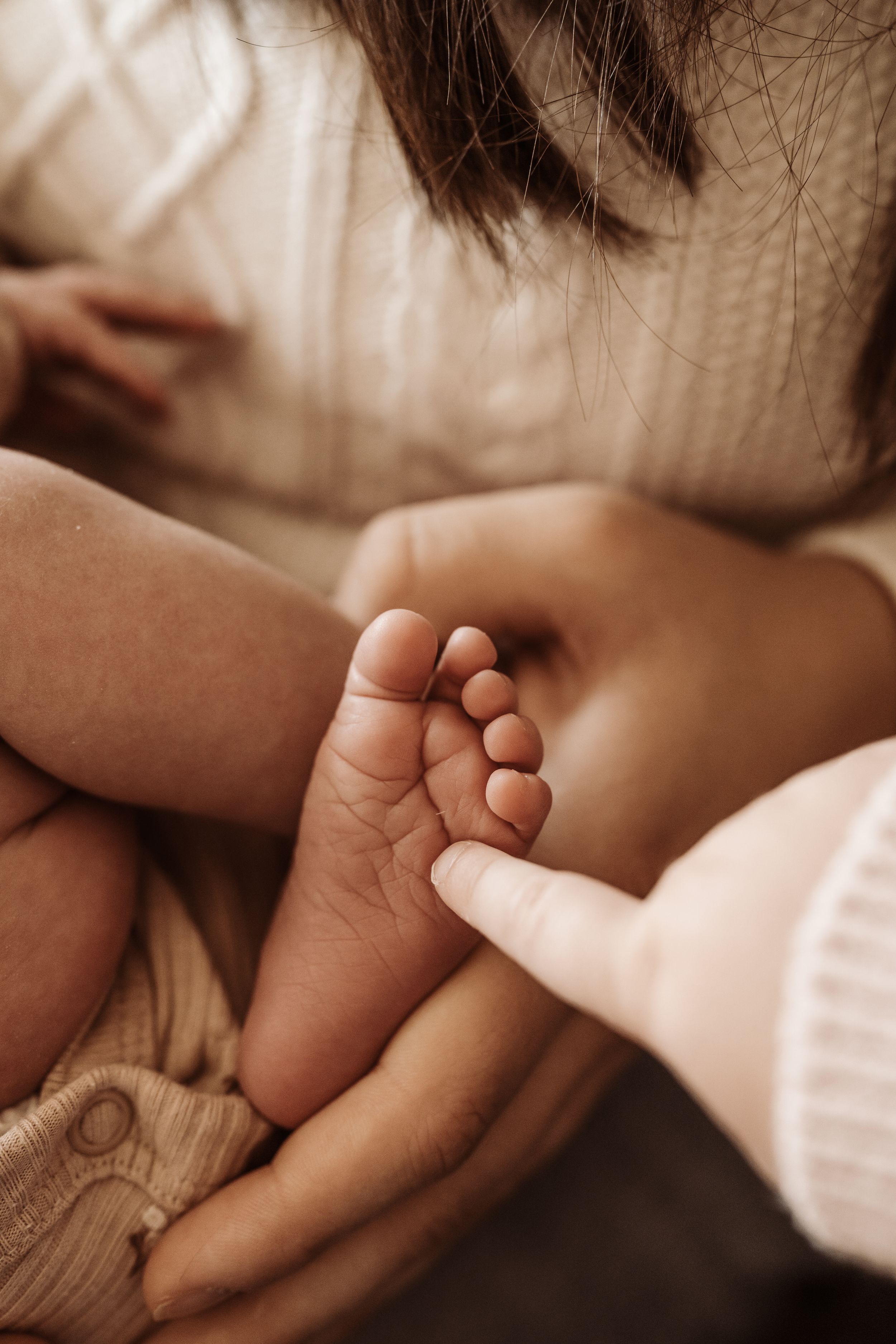 A tender moment captured in sepia tones as two hands gently touch and intertwine against a soft background.