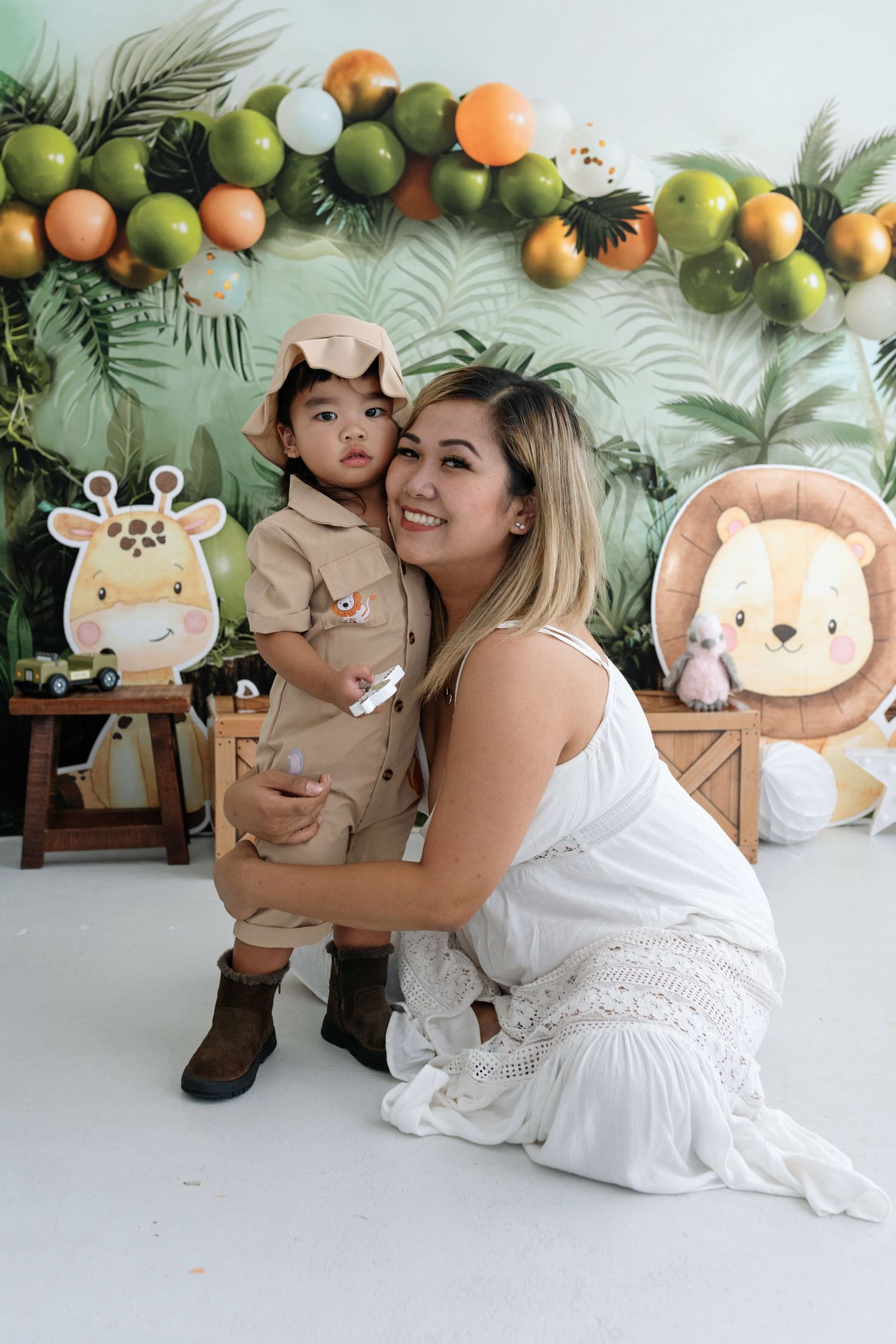A series of photos with safari-themed decorations including plush animal toys and balloon garlands against a tropical backdrop.