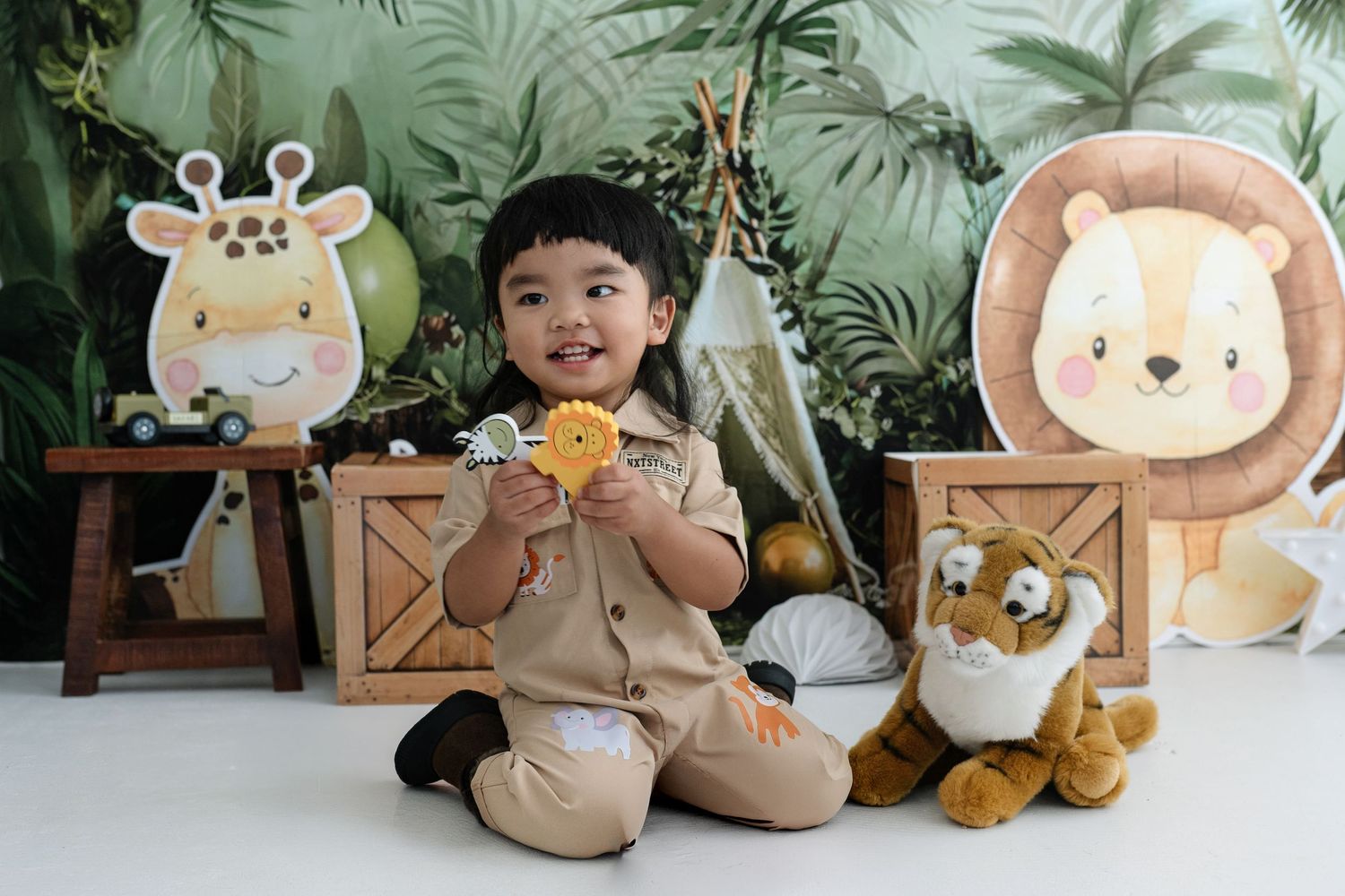 Plush toys and stuffed animals arranged in a cozy display against a green leafy backdrop.