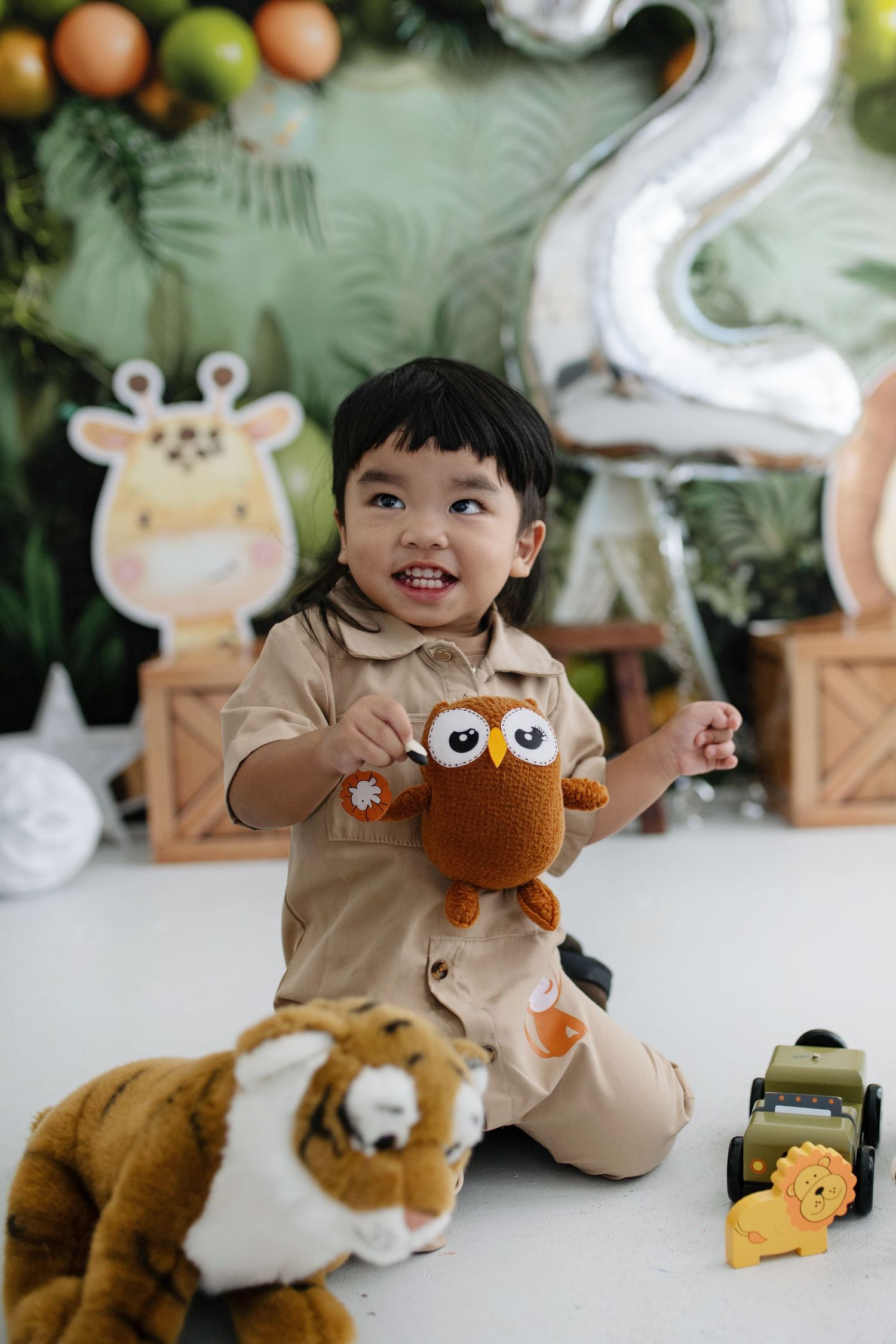 A child plays with stuffed animal toys and plush decorations in a bright indoor setting.