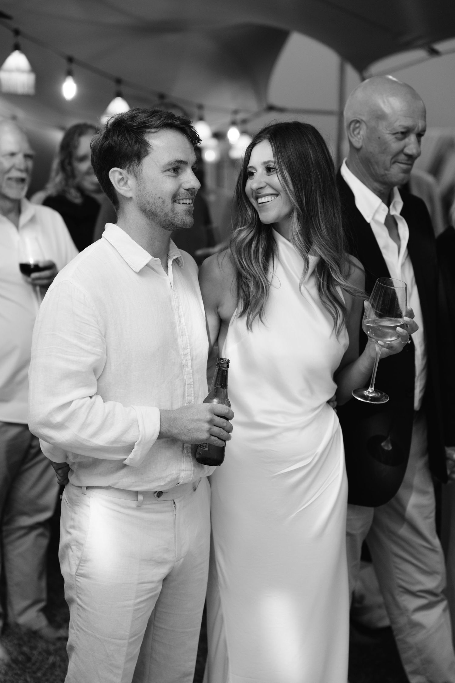 A black and white candid photo of guests enjoying themselves at an elegant wedding reception.