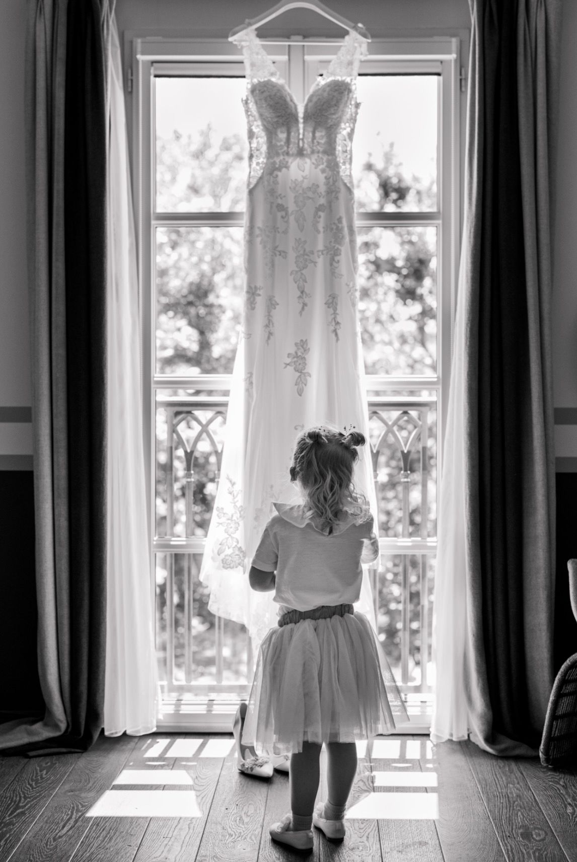 A black and white photo of wedding dresses hanging in windows creating a repeating pattern along a wall.